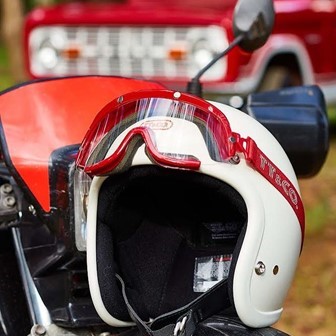 『TT&CO』の白色ヘルメットに赤いゴーグルをつけてシート上に置いている様子。