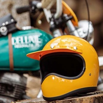黄色の『TT&CO』トゥーカッターヘルメットをバイク脇の切株の上に置いたところ