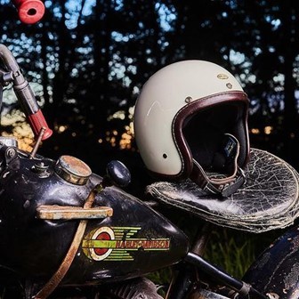 アイボリー色の『TT&CO』ヘルメットをカスタムバイクのシート上に置いて乗せたところ。