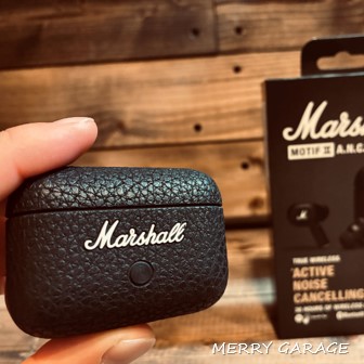 Marshall「Motif Ⅱ A.N.C」を指でつまんで持ち、バックに商品パッケージの箱が置いてある画像